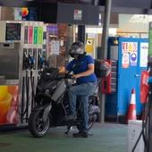 Una motocicleta parando en una gasolinera Una motocicleta parando en una gasolinera