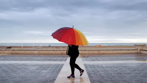 Una persona pasea por la playa en un día lluvioso. Una persona pasea por la playa en un día lluvioso.