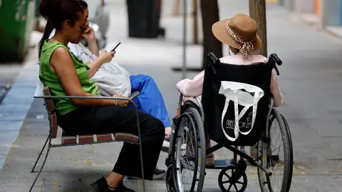 Una mujer cuidadora con una persona mayor sentada en una silla de ruedas en una imagen de archivo. Una mujer cuidadora con una persona mayor sentada en una silla de ruedas en una imagen de archivo.