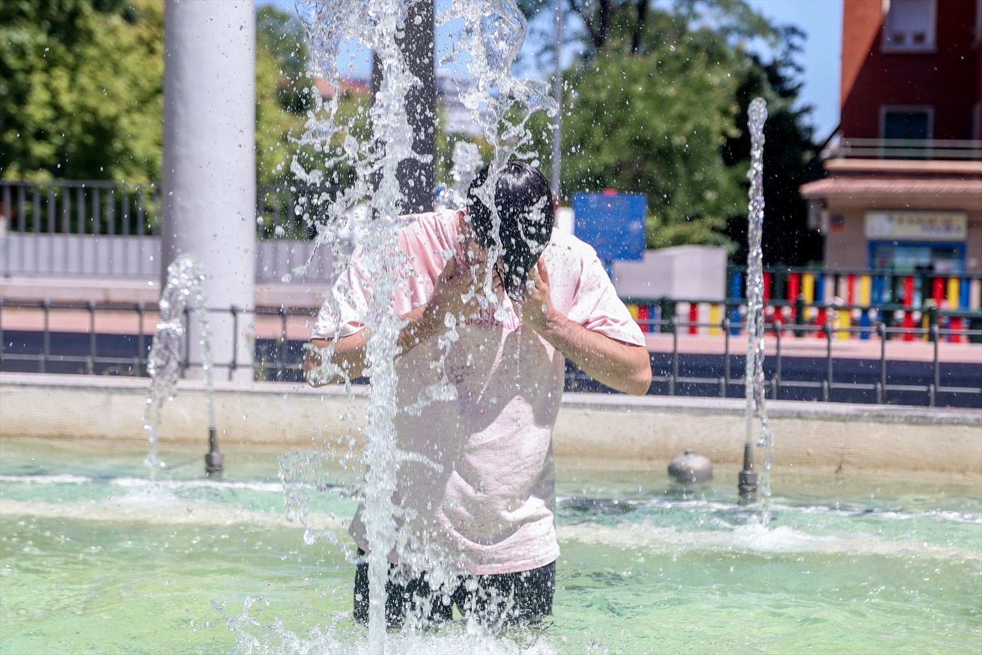 Una persona se refresca en una fuente Una persona se refresca en una fuente