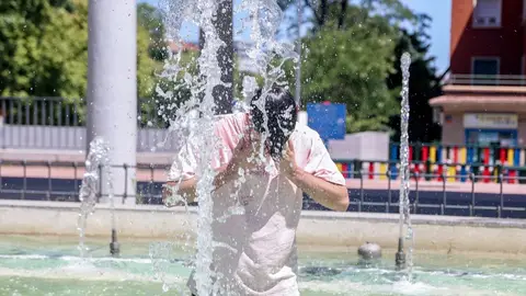 Una persona se refresca en una fuente Una persona se refresca en una fuente