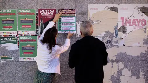 Dos profesores colgando un cartel de la huelga indefinida del profesorado Dos profesores colgando un cartel de la huelga indefinida del profesorado