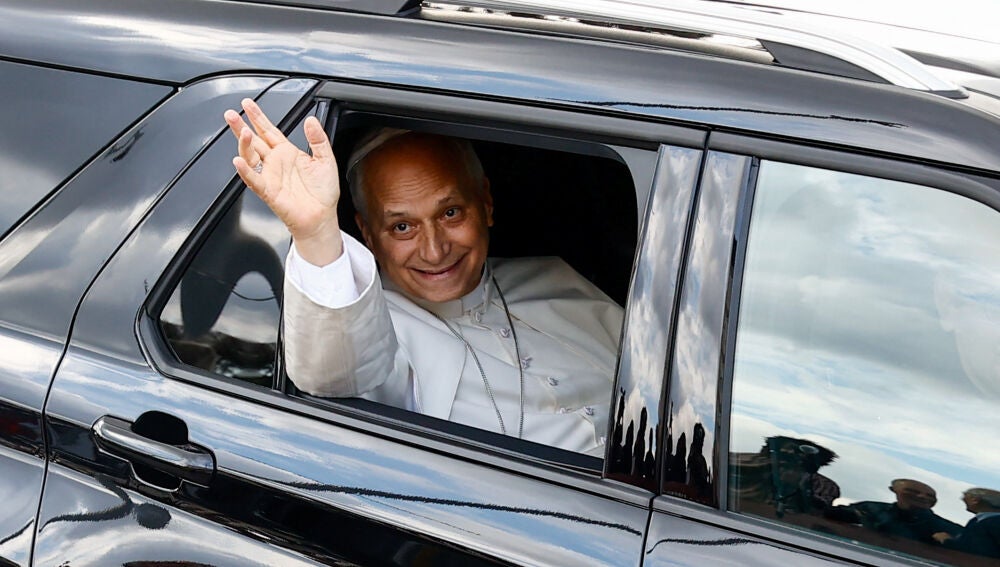 El papa León XIV sonriente y saludando a los fieles desde el coche que le lleva al Vaticano