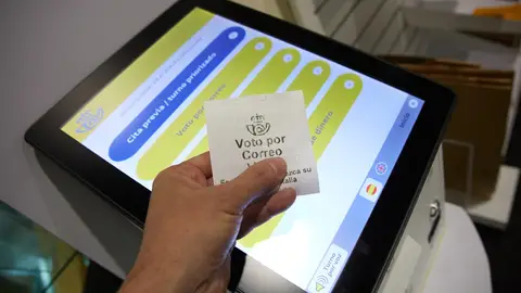 Una persona con un ticket de voto por correo en la oficina de Correos. Una persona con un ticket de voto por correo en la oficina de Correos.