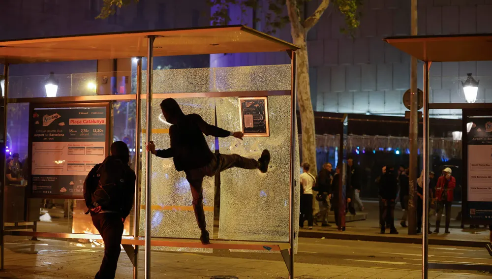 Protestantes en la plaza Catalunya en Barcelona rompiendo marquesinas de autobús Protestantes en la plaza Catalunya en Barcelona rompiendo marquesinas de autobús