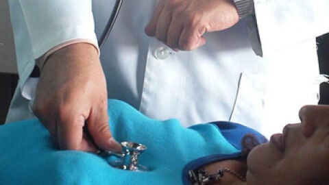 Un m&eacute;dico osculta a una paciente