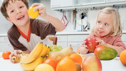 Dos ni&ntilde;os comiendo fruta