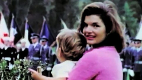 Jackie Kennedy posa con su hijo en brazos en un desfile militar.