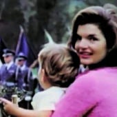 Jackie Kennedy posa con su hijo en brazos en un desfile militar.
