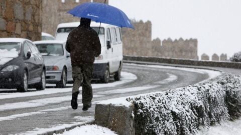 Un hombre corre con un paraguas para protegerse de la nieve en &Aacute;vila