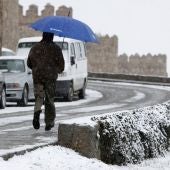 Un hombre corre con un paraguas para protegerse de la nieve en Ávila