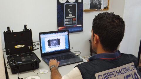 Agente analizando material ped&oacute;filo incautado al detenido. 