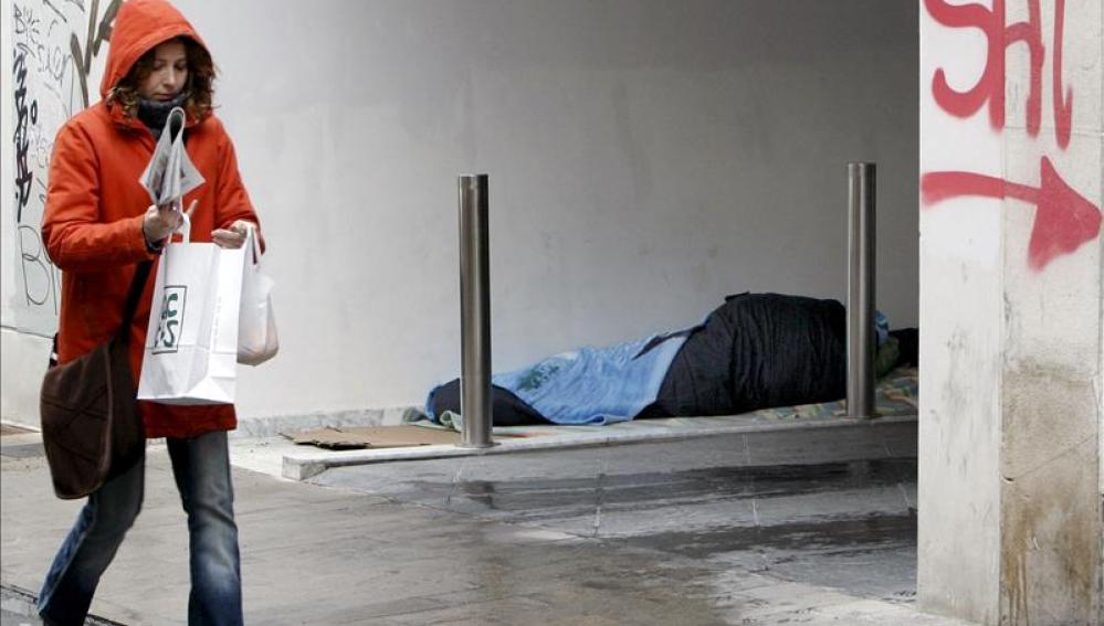 Un indigente duerme resguardado en un portal del centro de Valencia