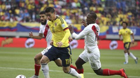 James Rodr&iacute;guez conduce el bal&oacute;n ante dos rivales peruanos