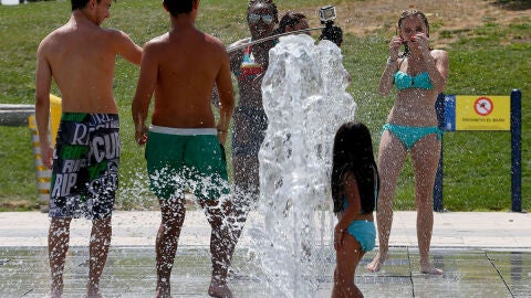 J&oacute;venes intentan aliviar el calor refresc&aacute;ndose en una de las fuentes del parque Juan Carlos I en Madrid