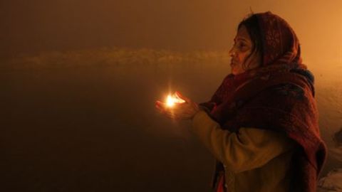 Una joven india sostiene una vela mientras reza despu&eacute;s de tomar un ba&ntilde;o sagrado en Sangam durante el festival Magh Mela. 