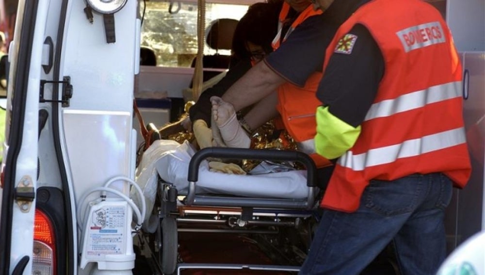 Los servicios médicos, ayudados por un bombero, atendiendo en un accidente
