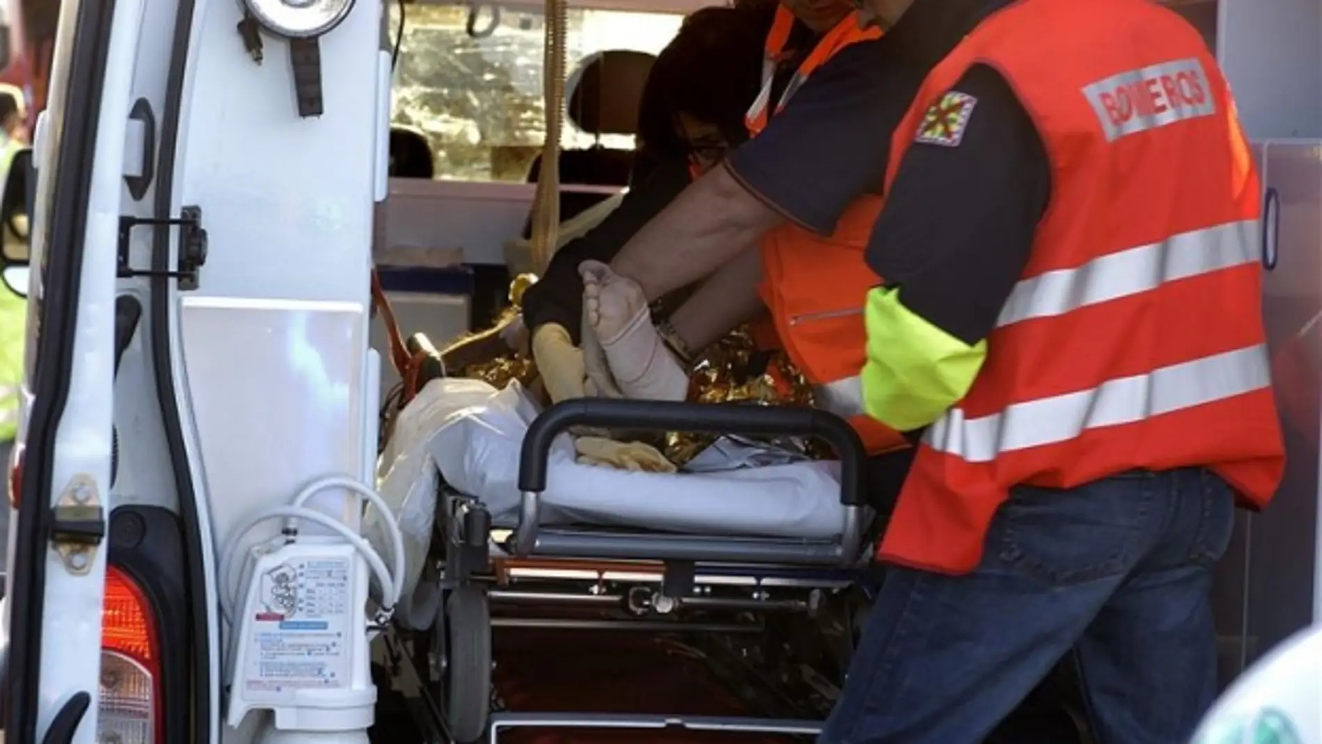 Los servicios médicos, ayudados por un bombero, atendiendo en un accidente