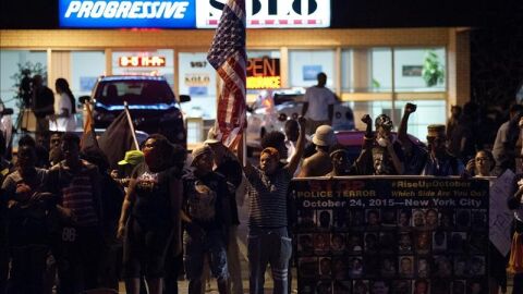 Manifestantes protestan con pancartas y banderas, para conmemorar el primer a&ntilde;o de la muerte del adolescente afroamericano Michael Brown Jr. en Ferguson, Missouri (EEUU).