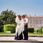 Dos personas bailan el tradicional chotis madrileño frente al Palacio Real de Madrid.
