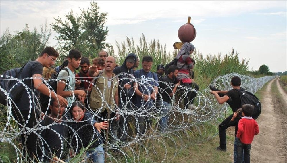 Varios refugiados sirios intentan saltar la alambrada de la frontera entre Hungría y Serbia