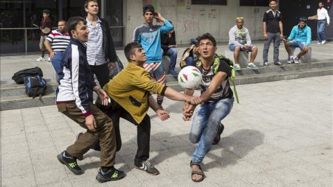 Varios refugiados juegan en la estaci&oacute;n de Budapest.