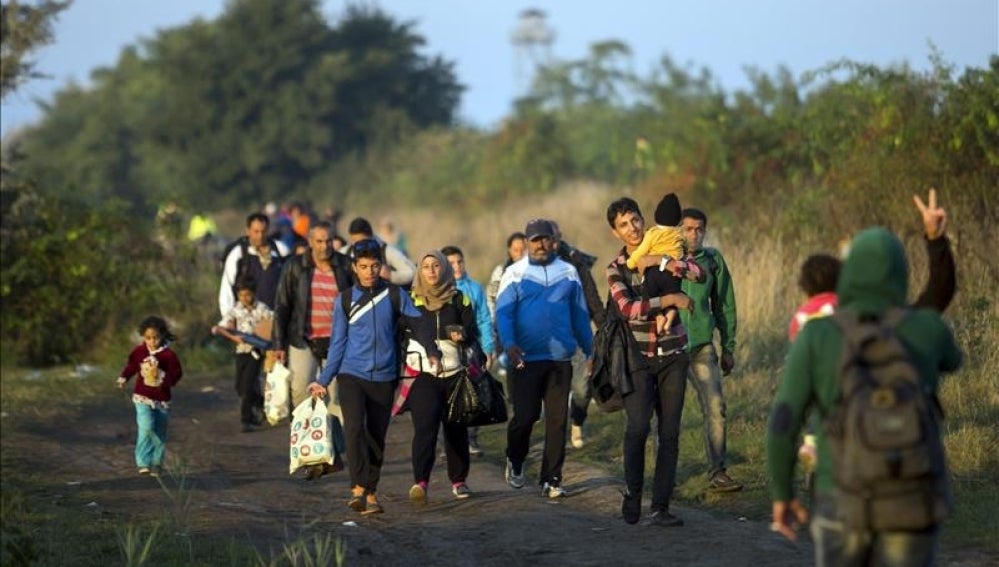 Varios refugiados caminan por las vías del tren en Hungría