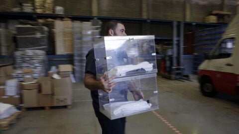 Un operario de la empresa encargada de repartir el material electoral trasnporta una urna en el almac&eacute;n municipal de Barcelona