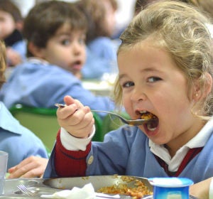 Niña comiendo en un comedor escolar Niña comiendo en un comedor escolar