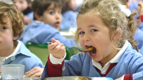Ni&ntilde;a comiendo en un comedor escolar