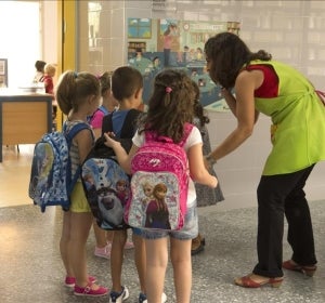 Varios niños entran al colegio con su profesora Varios niños entran al colegio con su profesora