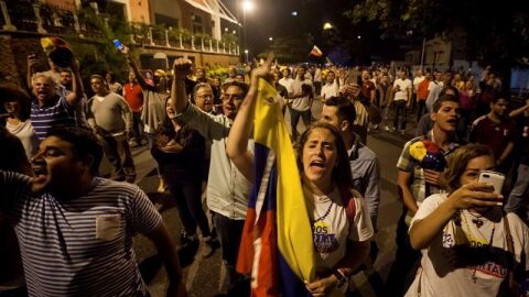 Un grupo de personas celebran la victoria obtenida por la coalici&oacute;n opositora Mesa de Unidad Democr&aacute;tica (MUD) en Venezuela