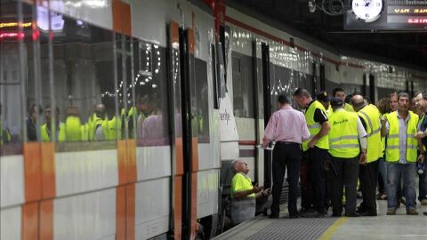 Trabajadores de RENFE revisan un tren en un and&eacute;n de una estaci&oacute;n en Barcelona.