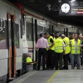 Trabajadores de RENFE revisan un tren en un andén de una estación en Barcelona.