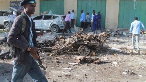 Un oficial de seguridad somal&iacute; pasa delante de los restos de un veh&iacute;culo tras una explosi&oacute;n en Mogadiscio