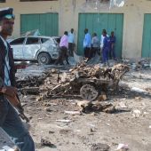 Un oficial de seguridad somalí pasa delante de los restos de un vehículo tras una explosión en Mogadiscio