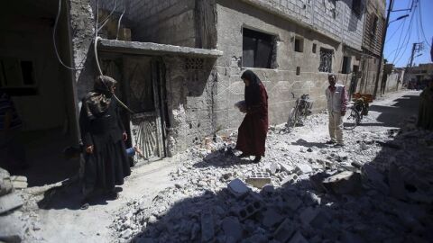 Varias personas inspeccionan edificios en ruinas tras los bombardeos en el pueblo de Deir al Asafi, al sureste de Damasco (Siria)