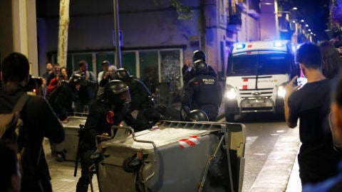 Varios antidisturbios retiran contenedores volcados en el barrio de Gr&agrave;cia, en Barcelona