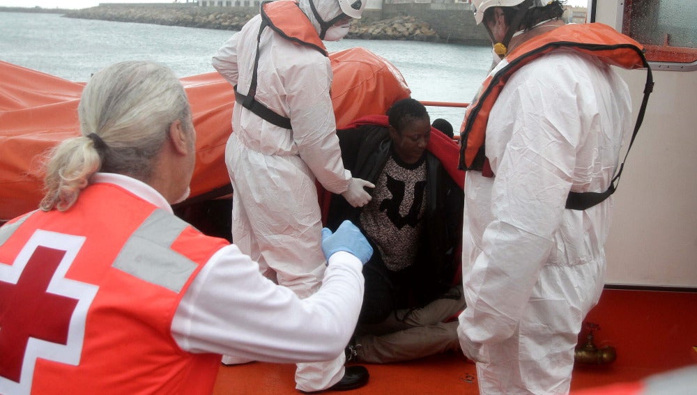 Personal de Cruz Roja ayudan a levantarse a unos inmigrantes que viajaban en una patera y que fueron rescatados por Salvamento Marítimo