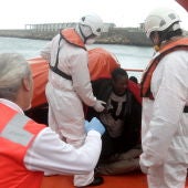 Personal de Cruz Roja ayudan a levantarse a unos inmigrantes que viajaban en una patera y que fueron rescatados por Salvamento Marítimo