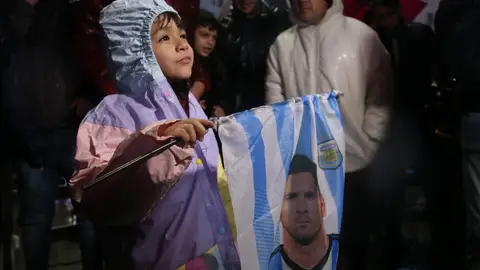 Un niño sostiene una bandera con la cara de Leo Messi Un niño sostiene una bandera con la cara de Leo Messi
