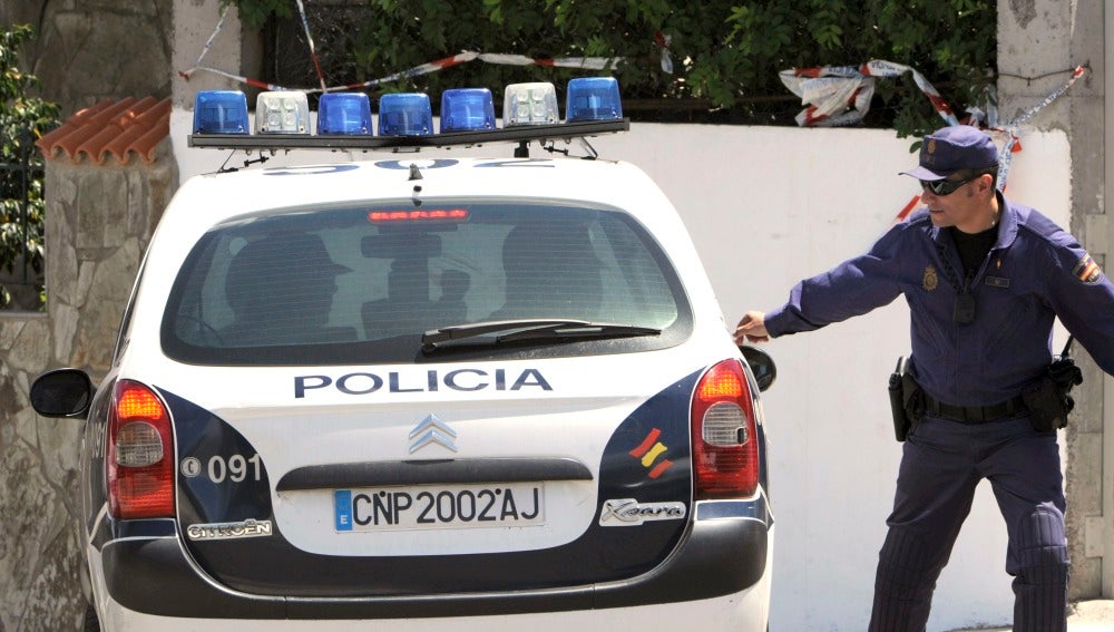 Un agente de Policía junto a un vehículo del cuerpo