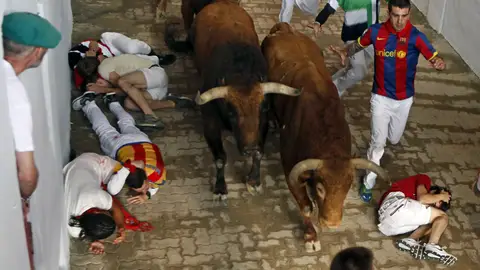 5º encierro | San Fermín 2016 Un grupo de mozos caen ante tres toros de la ganadería extremeña de Jandilla en el callejón de la Plaza de Toros de Pamplona durante el quinto encierro de los sanfermines 2016.