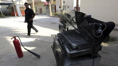 Un polic&iacute;a iraqu&iacute; camina junto a un extintor y una de las incubadoras quemadas en el incendio en un hospital del oeste de Bagdad