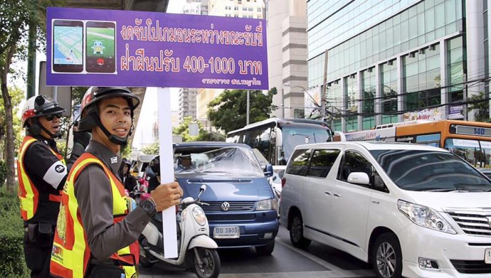  Un guardia de tráfico sostiene una pancarta en la que se lee "No juege a Pokemon Go mientras conduce"