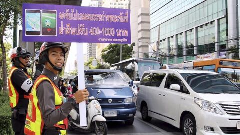  Un guardia de tr&aacute;fico sostiene una pancarta en la que se lee "No juege a Pokemon Go mientras conduce"