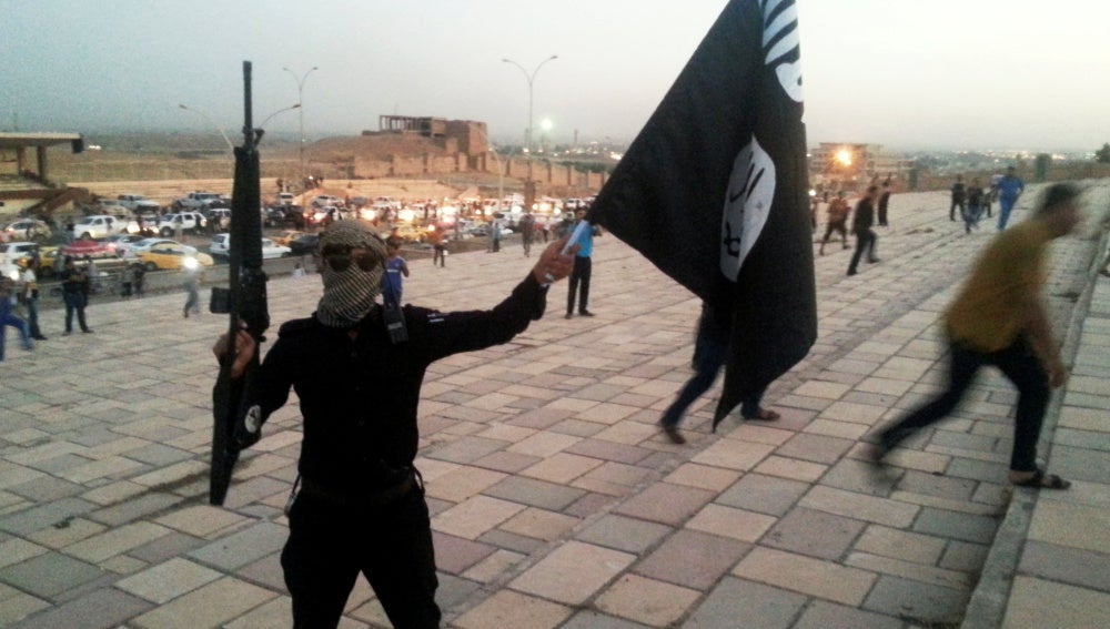 Un combatiente de Daesh sostiene una bandera y un arma en una calle de Mosul