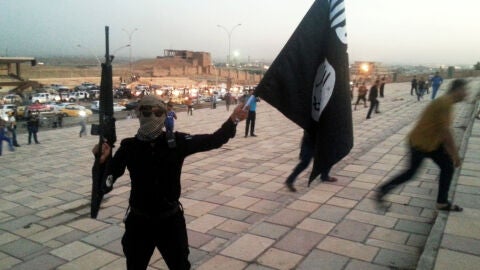 Un combatiente de Daesh sostiene una bandera y un arma en una calle de Mosul