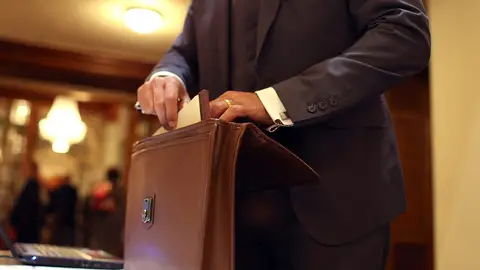 Un hombre sacando documentos de un maletín Documentos