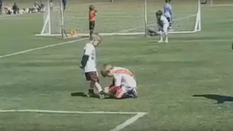 Un niño ayuda a otro a atarse la bota durante un partido en Argentina Un niño ayuda a otro a atarse la bota durante un partido en Argentina